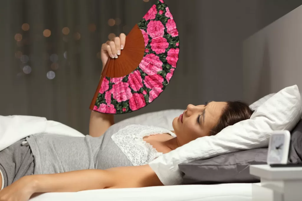 Woman lying in bed drenched in perspiration experiencing night sweats