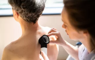 Doctor checking for non-melanoma skin cancers on a man's back