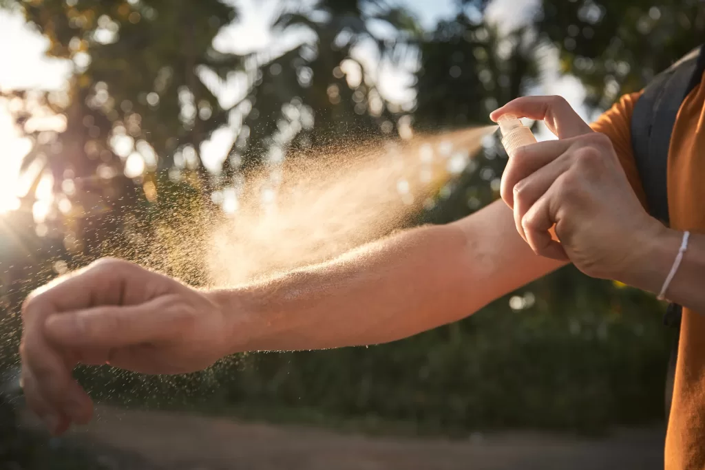 Man is applying insect repellent on his arm against dengue