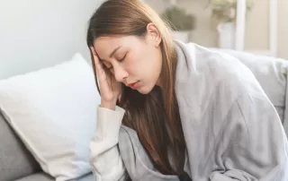 Woman with dengue touches her forehead having a headache and fever