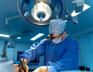 Young female doctor in white medical uniform with stethoscope using laptop for online consultation with a patient